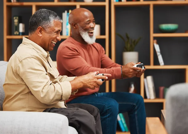 Gaming, fun and senior black man friends playing a video game together in the living room of a home. Sofa, funny or retirement with a mature male gamer and friend enjoying a house visit to game.