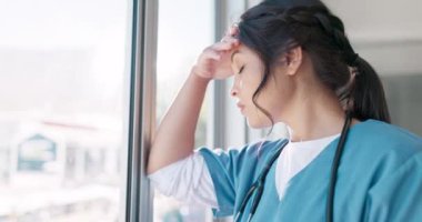 Woman doctor, headache and burnout by window with stress, tired or sad in hospital workplace with pain in head. Professional medic, mental health problem and clinic with anxiety from healthcare job.