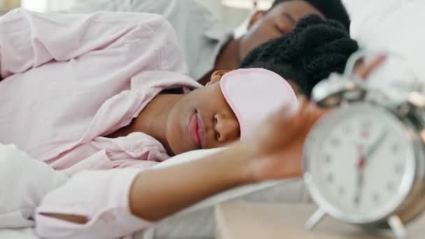 黒い女性が目を覚まし 目覚まし時計を家の中の睡眠マスクでオフにします 眠いとアフリカの女の子寝ていますで彼女の快適なベッドルームとともに早朝取得時間に自宅 — ストック動画