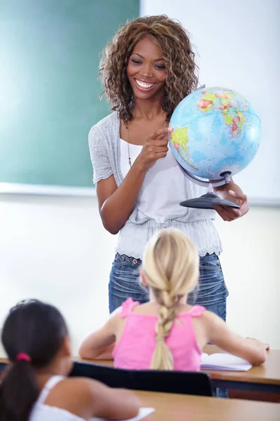 Who can tell me the name of this country. A young teacher showing her class a globe of the world during geography
