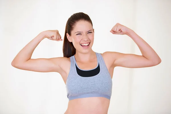 Young woman flexing her arm muscles, dressed in fitness clothing