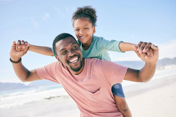 Child, black man and piggy back at ocean on playful family holiday in Australia with freedom, fun and energy. Travel, fun and happy father and girl with smile playing and bonding together on vacation.