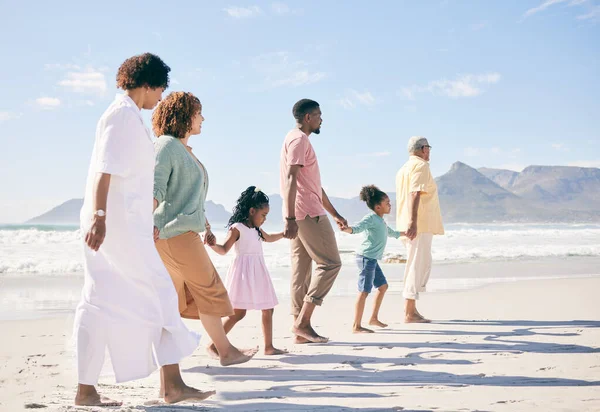 Family is walking on beach, travel and holding hands with generations, unity and freedom with love, together outdoor. Grandparents, parents and children, people on holiday with tropical destination.