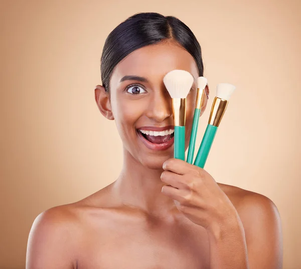 Girl, brushes or makeup artist with beauty, facial products or luxury self care on studio background. Wow, happy model face or excited young Indian woman with cosmetics, glowing skincare or smile.