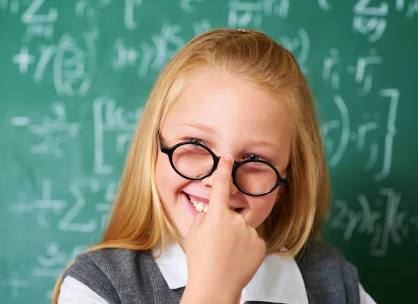Proud of her school achievements. A cute blonde girl adjusting her glasses in class