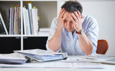 Unable to keep up with the load...a mature office worker looking tired as he works at his desk clipart