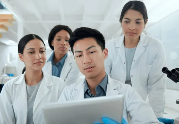科学是一个有竞争力的领域 一组在实验室里使用数字平板电脑的科学家 — 图库照片