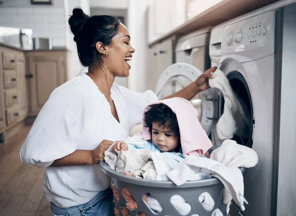 Mom loves it when I do the housework. a young mother playfully bonding with her baby girl while doing the laundry at home