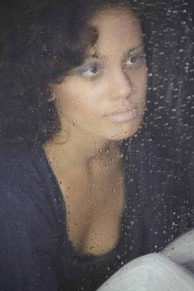 The dark side of depression. A sad young woman looking out at the rain
