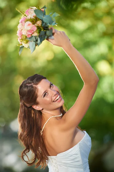 Whos the next to get hitched. Rearview shot of a happy young bride about to toss her bouquet over her shoulder