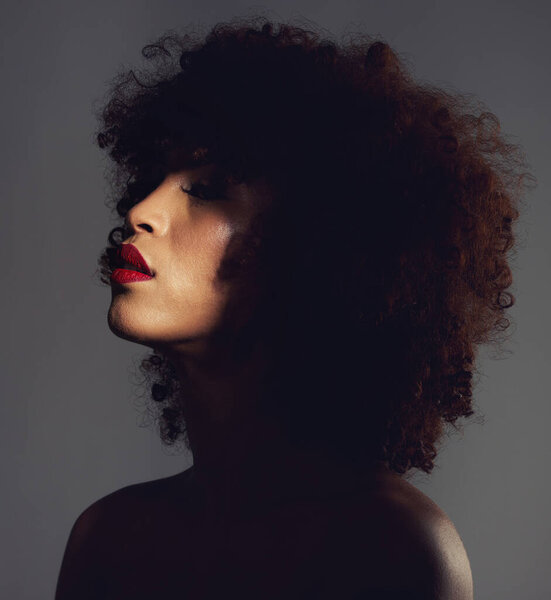 Beauty, shadow and woman with afro and makeup as skincare, cosmetic and self care in the dark or night. Spotlight, creative and face of female model with mystery aesthetic and luxury fashion.