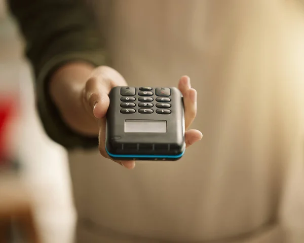 Closeup of hand of small business owner holding NFC card payment machine. Business owner holding an nfc machine. Creative entrepreneur using a contactless payment machine. Tailor using card machine.