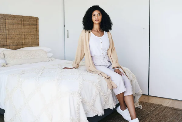 Black woman relax, bedroom and home interior of a young female sitting on a bed feeling relax. House, morning and person calm on a blanket and duvet on a mattress getting ready for a nap and day rest.