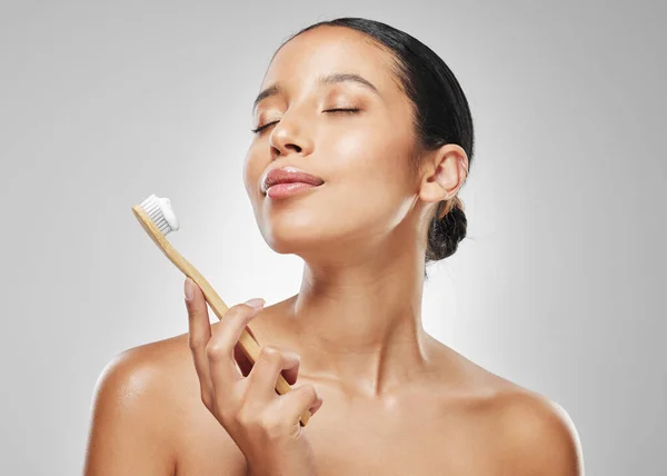 stock image Minty, fresh breath is the best. Studio shot of an attractive young woman brushing her teeth against a grey background