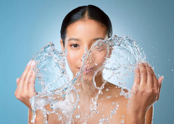 Stock image Goodbye dry skin. an attractive young woman posing against a blue background in the studio and splashing her face with water