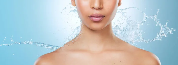 Treat your skin as if its an investment. an unrecognisable woman posing against a blue background in the studio while being splashed with water