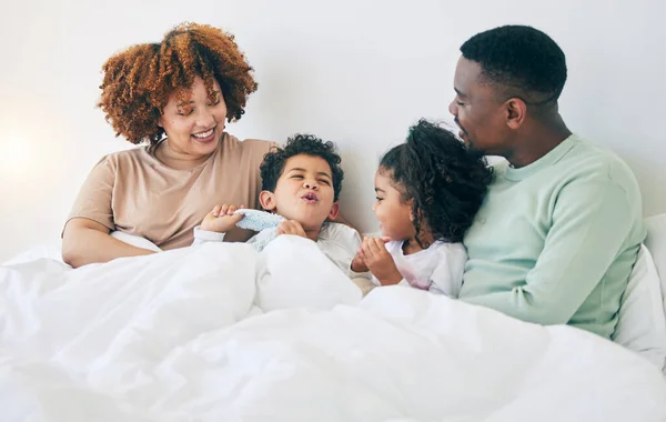 stock image Happy, love and parents with children in bed enjoy morning for bonding, quality time and relaxing. Black family, bedroom and mother, father and kids playing on holiday, weekend and vacation at home.