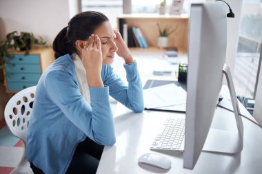 Zihni ona karşı isyan ediyor. Modern bir ofisteki masasında dizüstü bilgisayar kullanan genç bir iş kadını stresli görünüyor.