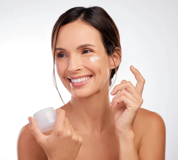 stock image Do you want to try some. an attractive young woman applying moisturiser to her face in the studio