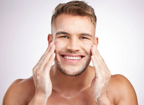 A clean face makes me feel good. Studio shot of a young man washing his face against a grey background
