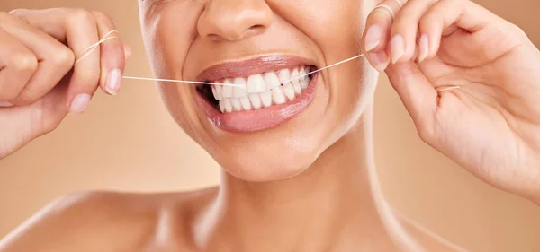 Flossing, smile and a woman with dental care for teeth isolated on a studio background. Happy, healthcare and the mouth of a girl with a routine oral hygiene cleaning, treatment and tooth floss.