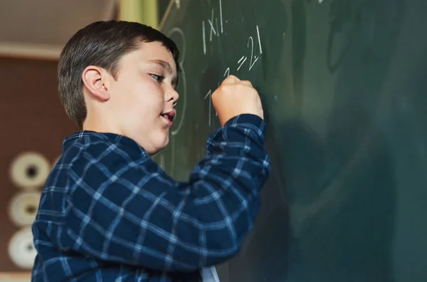 私はこれらの答えをすべて知っている 一人で立って黒板に書いている少年が学校の教室で — ストック写真