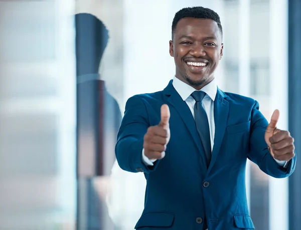 Id love to work with a winner like you. a young businessman showing thumbs up in a modern office