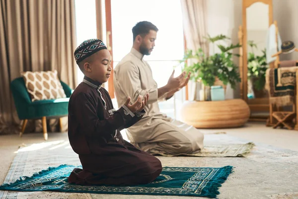 同胞愛と献身の美しい宗教 若いイスラム教徒の男性と息子が自宅のラウンジで祈り — ストック写真