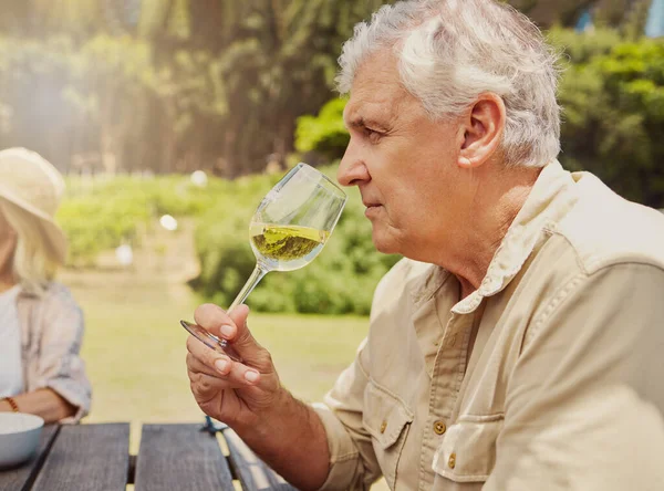 Starszy Biały Mężczyzna Siedzący Wąchający Kieliszek Białego Wina Podczas Degustacji — Zdjęcie stockowe
