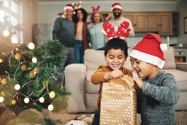 Christmas, curious and children opening gifts, looking at presents and boxes together. Smile, festive and kids ready to open a gift or present under the tree for celebration of a holiday at home.