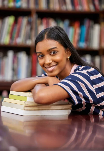 Success is the progressive realisation of a worthy goal. a young woman resting on a pile of books in a college library