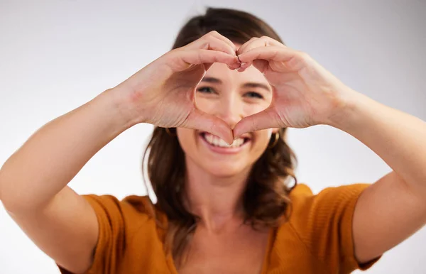 Good vibes only. Studio shot of a young woman showing a heart sign with her hands against a white background