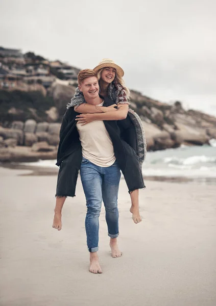 I love how I can be myself with you. a man piggybacking his girlfriend while walking on the beach