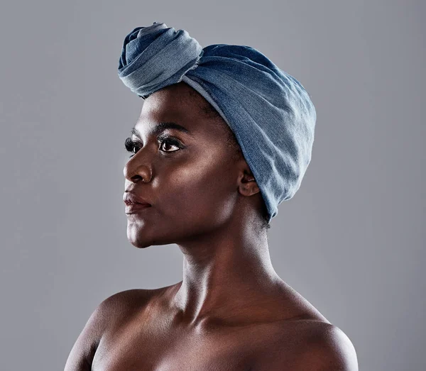 Crowns come in many shapes and forms. a beautiful young woman wearing a denim head wrap while posing against a grey background