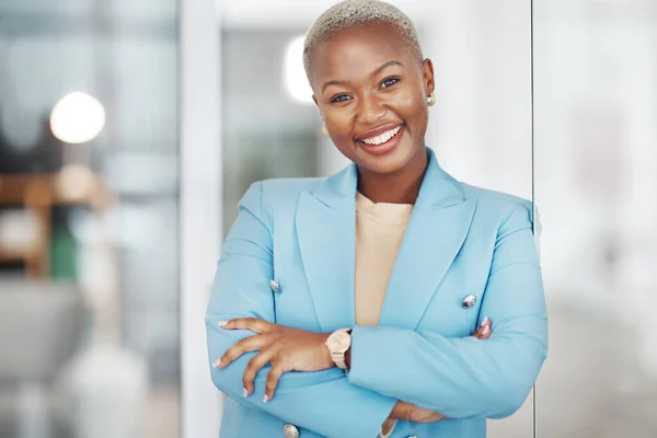 Black woman, portrait smile and arms crossed in small business management leaning on glass in modern office. Happy African American female smiling in confidence for corporate success at the workplace.