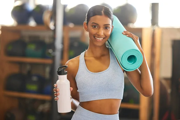stock image Get ready, things are about to get sweaty. Portrait of a fit young woman holding an exercise mat and water bottle in a gym
