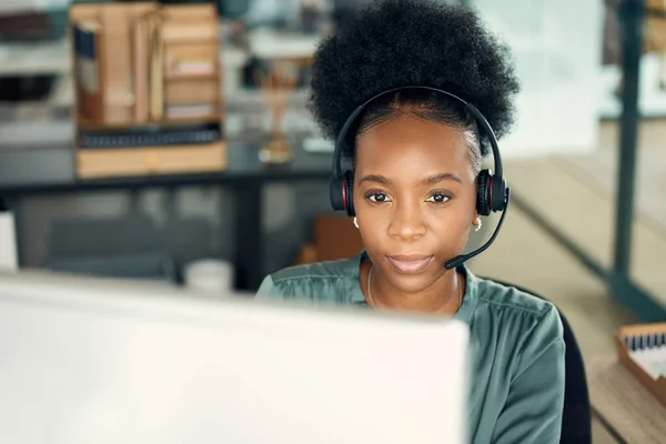 Let me review the issue on my end...a young businesswoman wearing a headset while working on a computer in an office