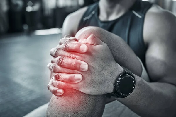 膝关节扭伤 运动员把受伤的膝盖抱在关节上 健美运动员膝盖抽筋 坐在体育馆里 身体压力会导致肌肉问题 关心你的身体肌肉 — 图库照片
