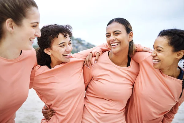 Friends, cheerful women and beach with hug for comic laugh, happy team and motivation for smile, support and diversity. Gen z athlete group, embrace and funny with solidarity, exercise and wellness.