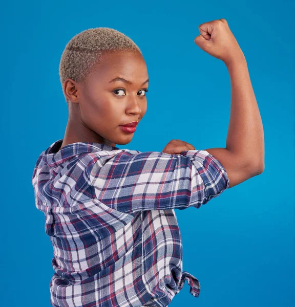 Portrait, black woman and flex arms on blue background, studio and backdrop of freedom, empowerment or pride. Female model, bicep and girl power in fight of gender equality, strong muscle or feminism.