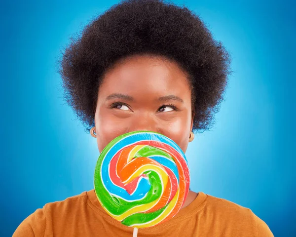 Sweet, happiness and black woman with lollipop, excited and lady on blue studio background. African American female, candy and girl with dessert, happy and cheerful with joy, treat and confectionary.