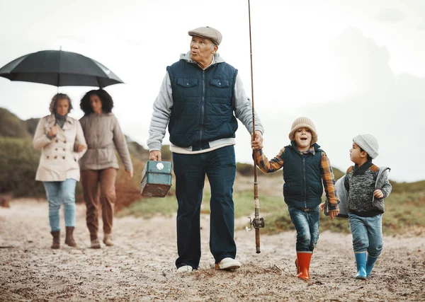 stock image Family, fishing vacation and man, women and happy kids at ocean, weekend hobby and fun together. Grandparents, mom and excited children walking at beach or lake on winter holiday adventure in nature