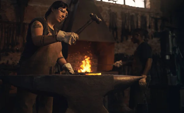 铁匠来之前 金属就是金属 在铸造厂用铁锤击打热金属棒的年轻女子 — 图库照片