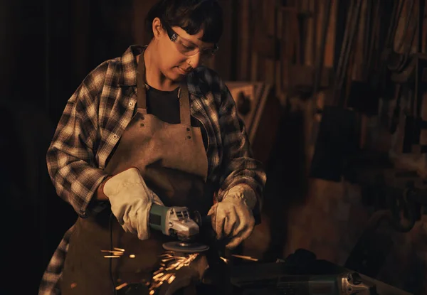 用她的工作开拓了新的领域 在铸造厂工作时使用角磨床的年轻妇女 — 图库照片