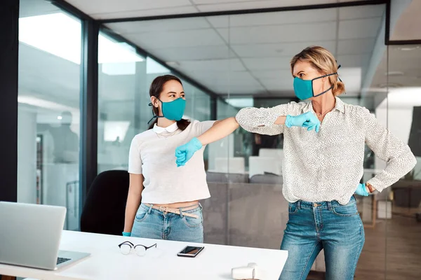 Keep safe in the workplace. two businesswomen bumping elbows in an office
