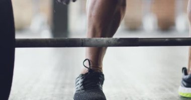 Closeup of muscular male bodybuilder hands and legs lifting heavy weights with chalk powder in sports centre gym. Man keeping fit, doing strength training and muscle growth exercises