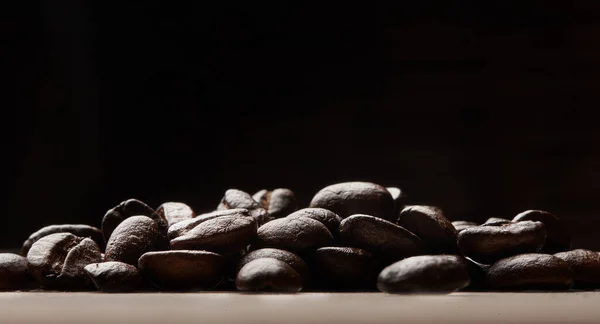 Experience love at first sip. Still life shot of coffee beans on a wooden countertop against a black background