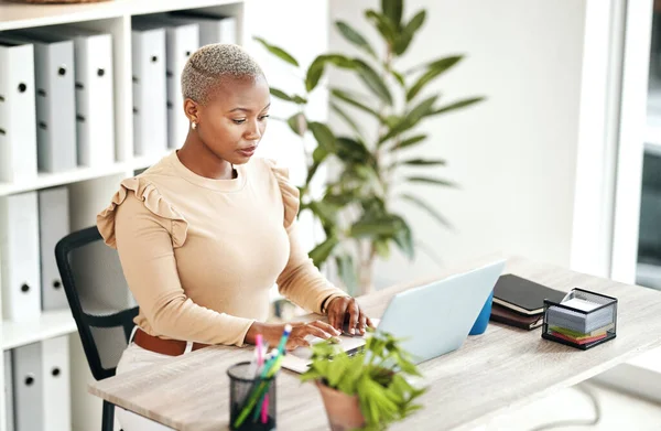 Serious black woman, laptop and business at desk, online research and planning strategy. Young female worker typing on computer technology for administration, digital management and project update.