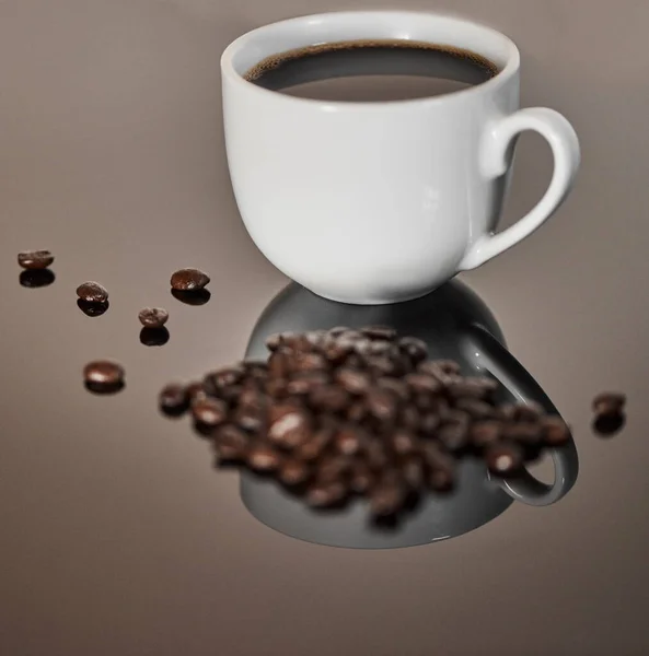 新鮮な豆から最高のブレンド 反射面に黒コーヒーとコーヒー豆のカップの閉鎖ショット — ストック写真