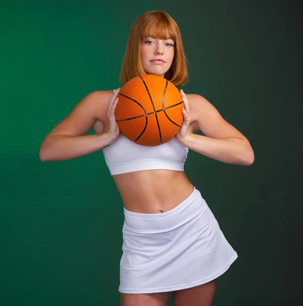 让我们一起玩吧一位年轻貌美的女运动员独自站在演播室里 拿着一个绿色背景的篮球 — 图库照片